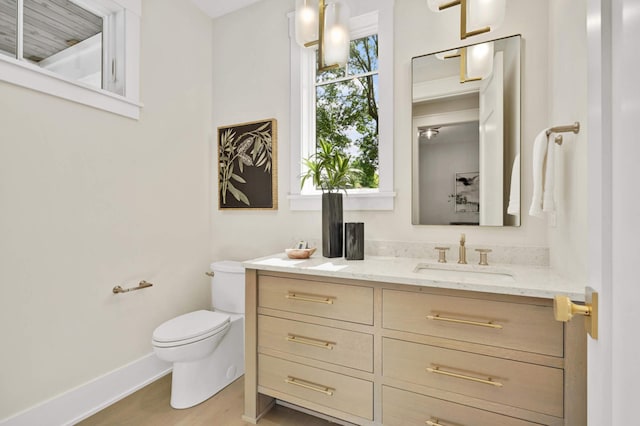 bathroom with wood finished floors, vanity, toilet, and baseboards