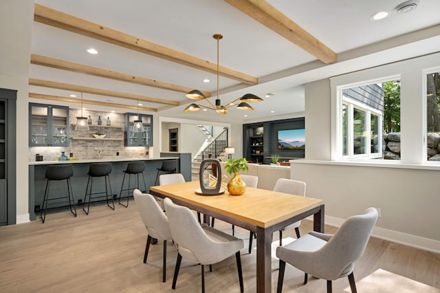 dining room with beamed ceiling, recessed lighting, light wood-type flooring, stairs, and bar