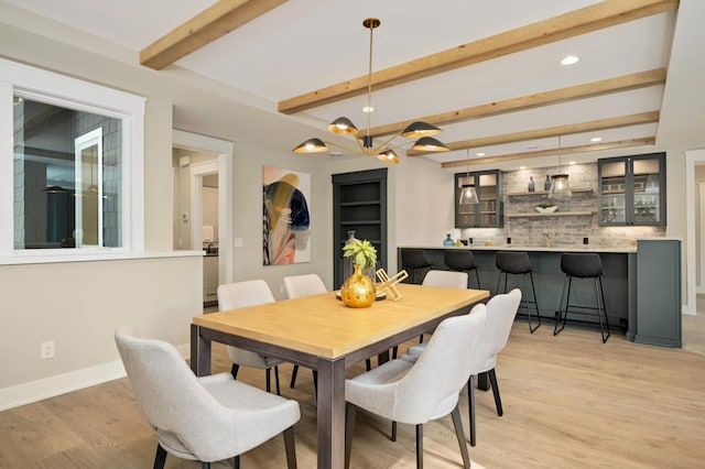 dining space with recessed lighting, light wood-style flooring, beamed ceiling, indoor wet bar, and baseboards