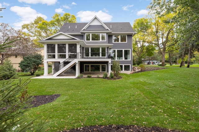 back of house with a yard, a shingled roof, a sunroom, and stairs
