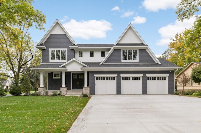 craftsman house featuring a shingled roof, driveway, an attached garage, and a front yard