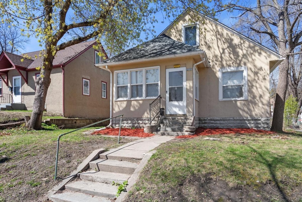 3343 Russell Ave N, Minneapolis, MN 55412 - bungalow-style home with stucco siding, a front yard, and entry steps