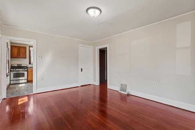 unfurnished room with baseboards, visible vents, wood finished floors, and ornamental molding