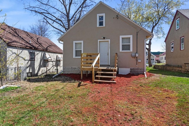 rear view of house with a lawn and stucco siding