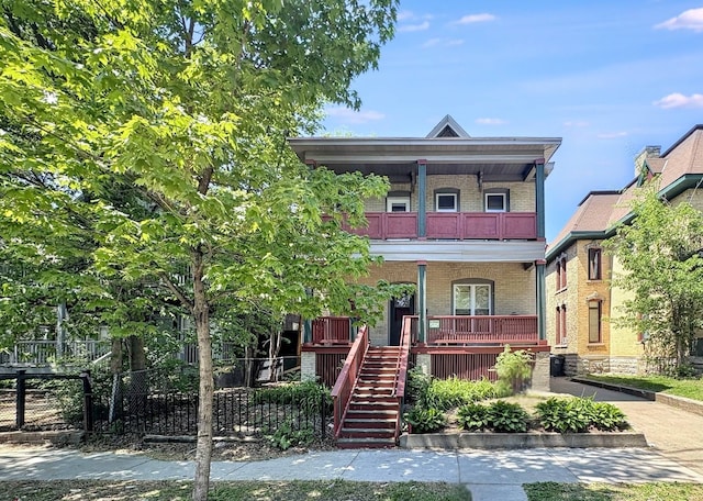 2108 Elliot Ave, Minneapolis, MN 55404 - view of front of property featuring a balcony, covered porch, brick siding, fence, and stairs