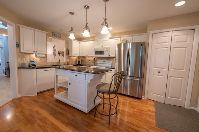 kitchen with dark countertops, backsplash, white cabinetry, and white appliances