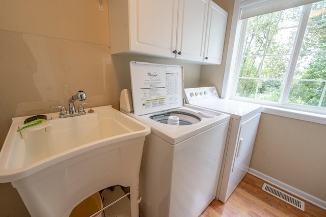 laundry area featuring a sink, cabinet space, light wood-style floors, visible vents, and washer and dryer