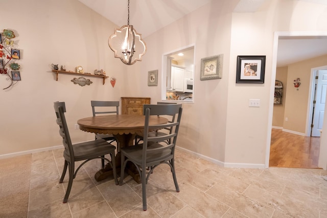 dining area featuring an inviting chandelier, lofted ceiling, and baseboards