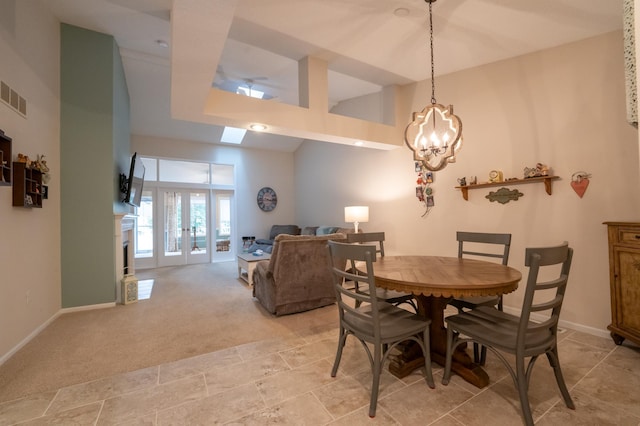 dining space featuring visible vents, an inviting chandelier, light carpet, a towering ceiling, and french doors