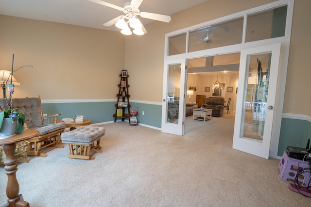 living area featuring a ceiling fan, french doors, and carpet flooring