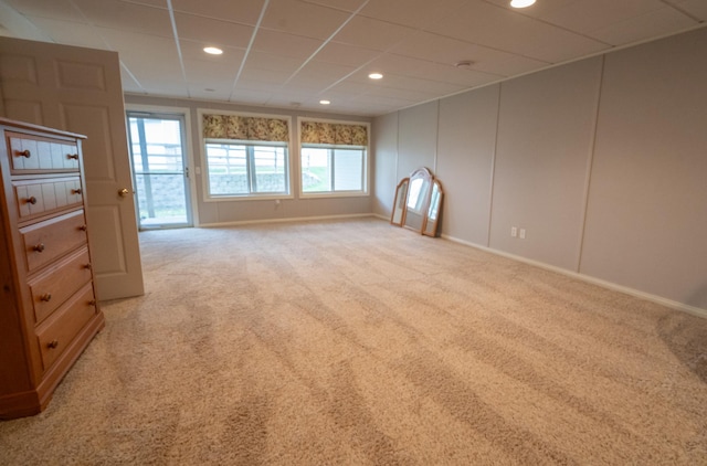 unfurnished living room with baseboards, recessed lighting, light carpet, and a drop ceiling