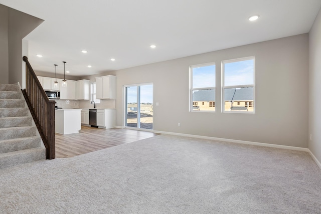 unfurnished living room with baseboards, recessed lighting, and light carpet