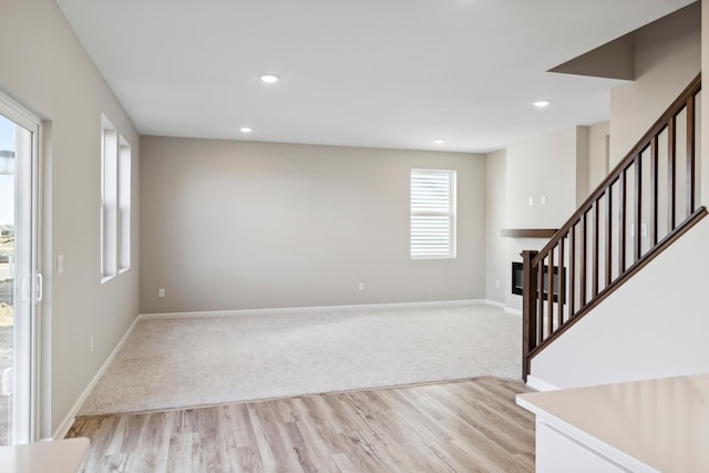 interior space featuring baseboards, recessed lighting, wood finished floors, and a glass covered fireplace