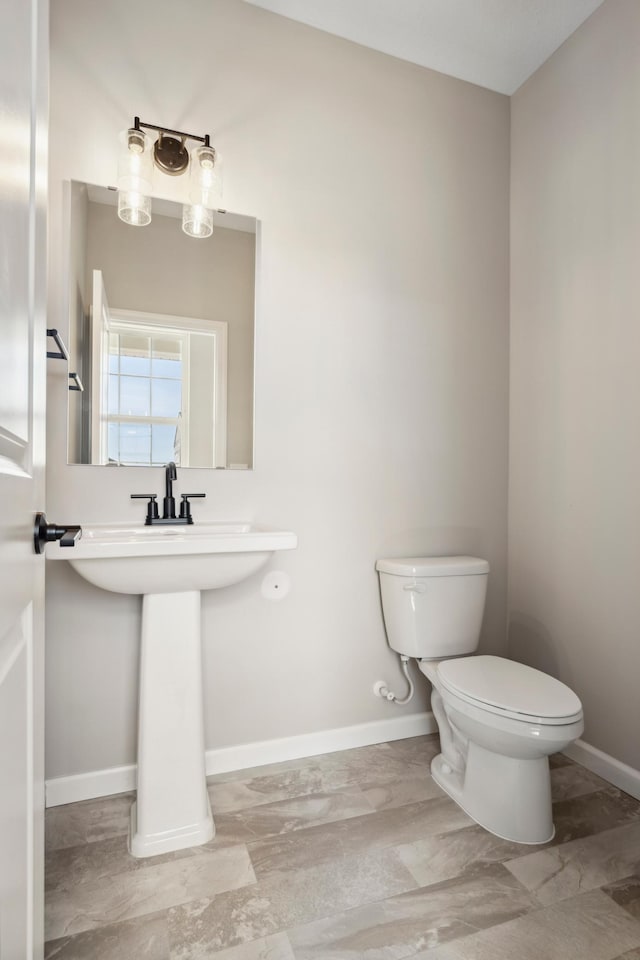 half bathroom with toilet and baseboards