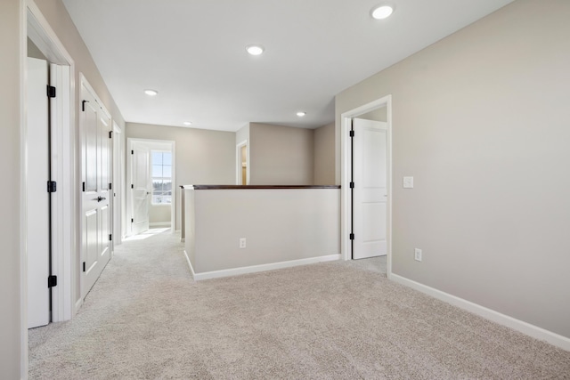 unfurnished room with baseboards, recessed lighting, and light colored carpet
