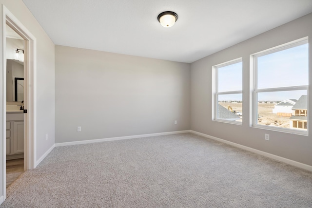 carpeted spare room featuring baseboards