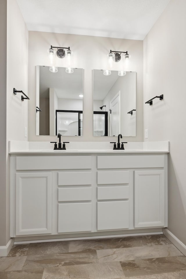full bathroom with double vanity, a sink, and baseboards