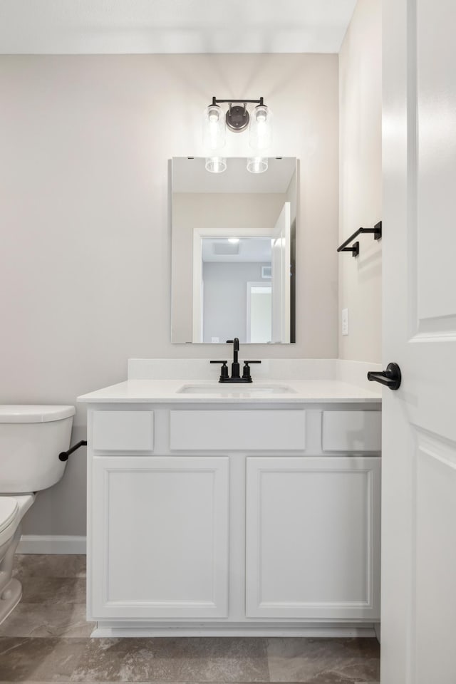 bathroom featuring baseboards, toilet, and vanity