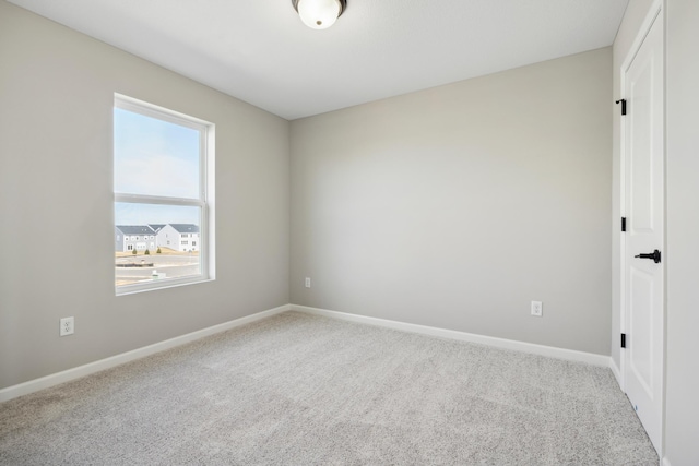 carpeted spare room featuring baseboards