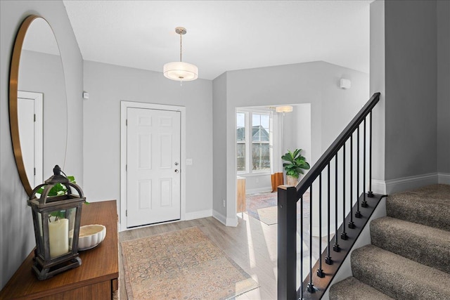 entryway featuring stairway, wood finished floors, and baseboards