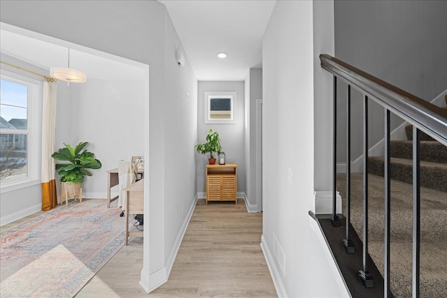 hall featuring baseboards, recessed lighting, stairway, and light wood-style flooring