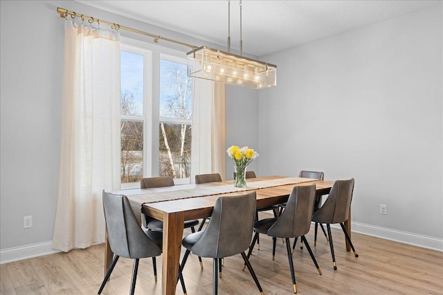 dining room with a notable chandelier, light wood-style flooring, and baseboards