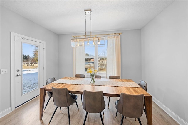 dining room with an inviting chandelier, baseboards, and light wood-style floors