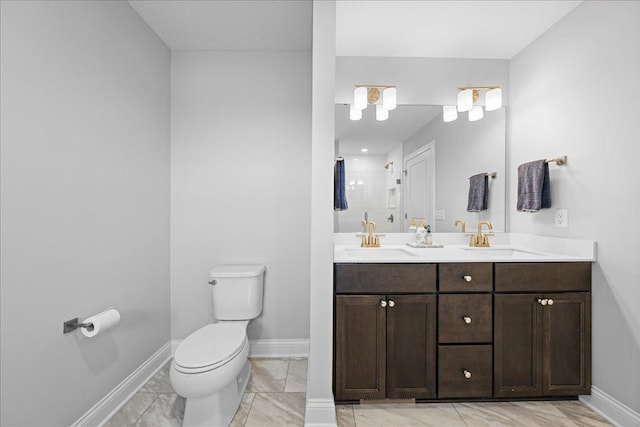bathroom featuring toilet, baseboards, a shower stall, and a sink
