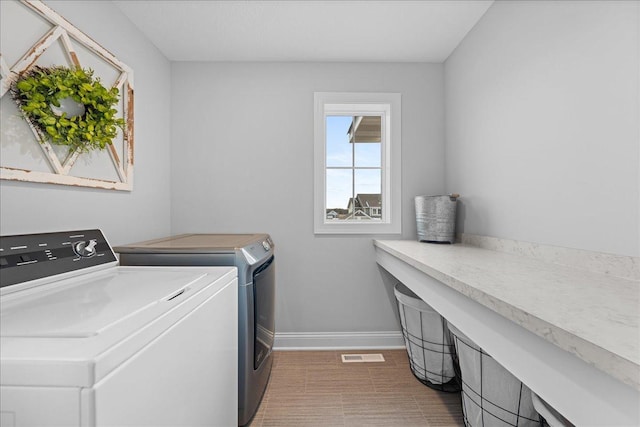 laundry room featuring baseboards, visible vents, washing machine and clothes dryer, and laundry area