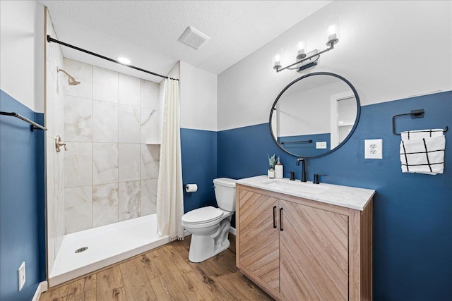 bathroom with a shower stall, vanity, toilet, a textured ceiling, and wood finished floors