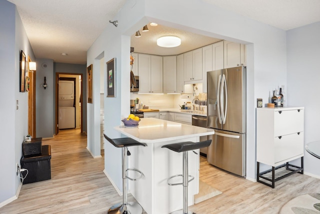 kitchen featuring light countertops, stainless steel appliances, a sink, and light wood-style flooring