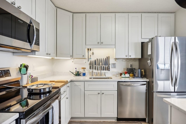 kitchen with a sink, white cabinetry, appliances with stainless steel finishes, and light countertops