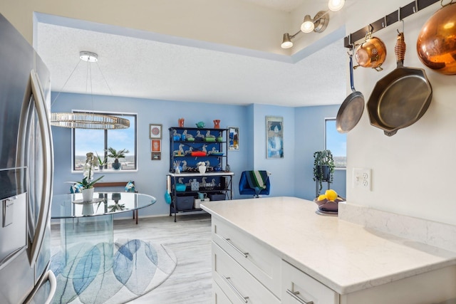 kitchen featuring freestanding refrigerator, white cabinets, a healthy amount of sunlight, and light wood-type flooring