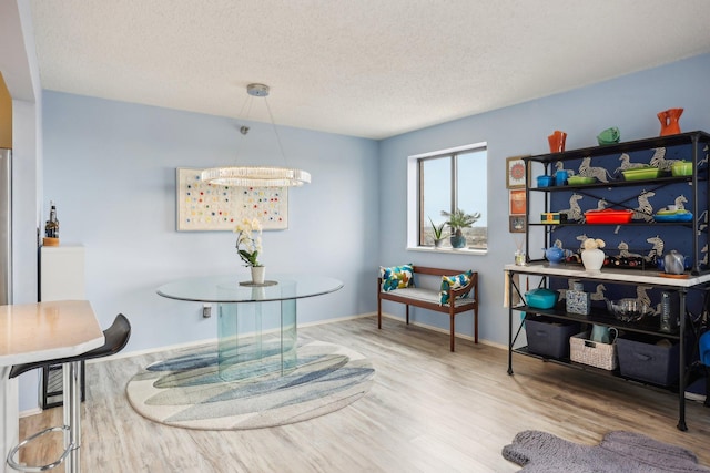 dining space with baseboards, a textured ceiling, and wood finished floors