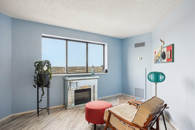 living area featuring visible vents, a textured ceiling, and wood finished floors