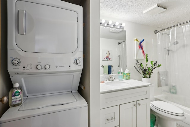 bathroom with stacked washer / drying machine, vanity, shower / bath combo with shower curtain, a textured ceiling, and toilet