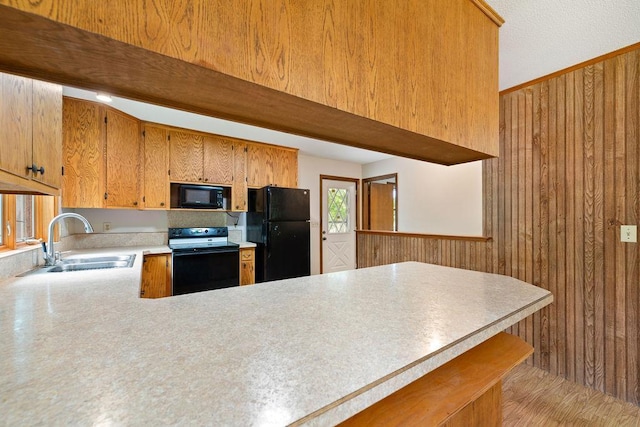 25431 Larch St NW, Isanti, MN 55040 - kitchen with black appliances, light countertops, a peninsula, wooden walls, and brown cabinetry