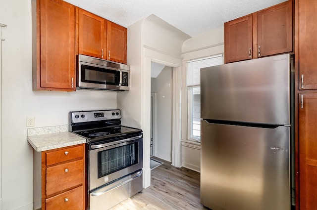 1040 26th Ave SE, Minneapolis, MN 55414 - kitchen featuring light wood-type flooring, appliances with stainless steel finishes, a wealth of natural light, and light countertops