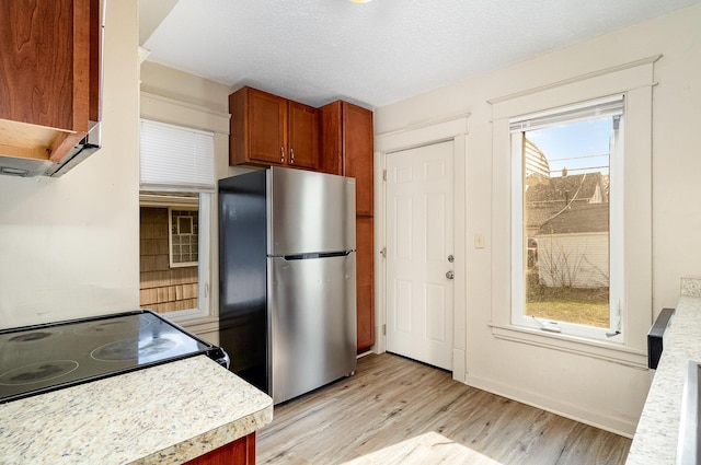 1040 26th Ave SE, Minneapolis, MN 55414 - kitchen featuring light wood finished floors, electric range oven, brown cabinetry, light countertops, and freestanding refrigerator