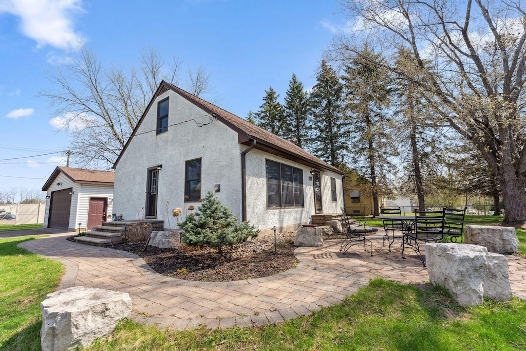 view of property exterior with a garage, stucco siding, and a patio area