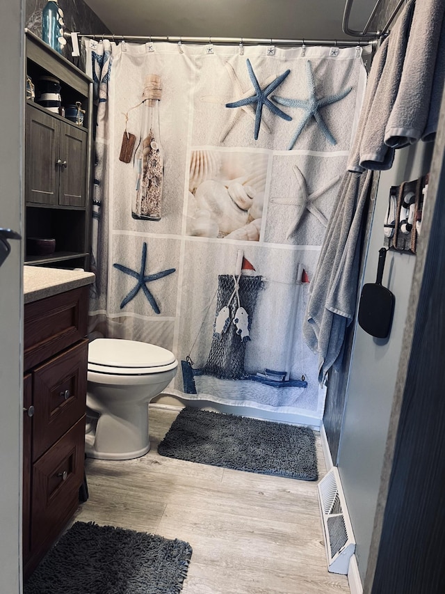 full bathroom featuring wood finished floors, a shower with shower curtain, toilet, vanity, and visible vents
