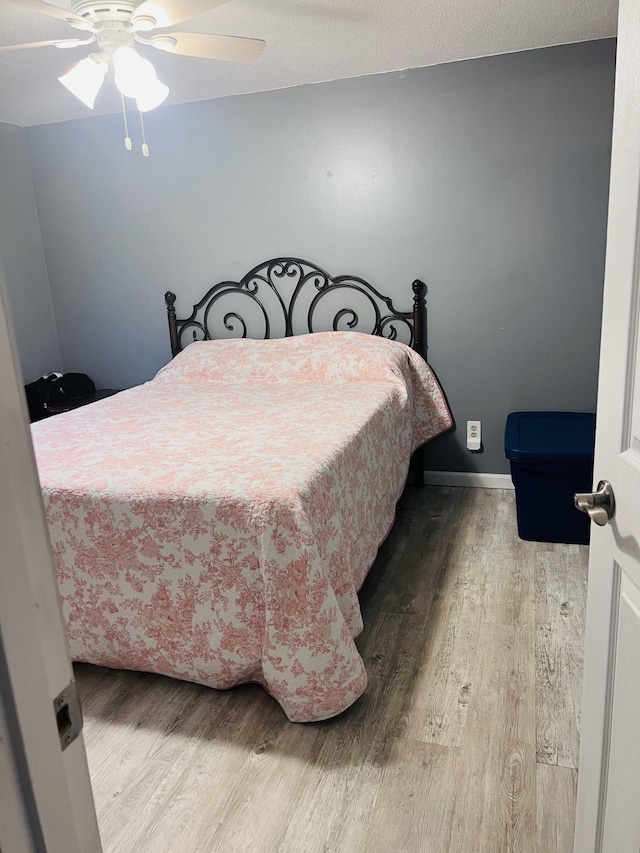 bedroom featuring wood finished floors, a ceiling fan, and baseboards