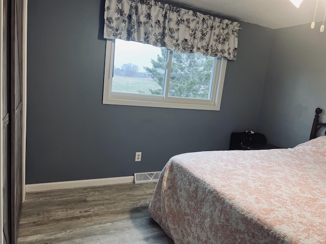 bedroom with wood finished floors, visible vents, and baseboards