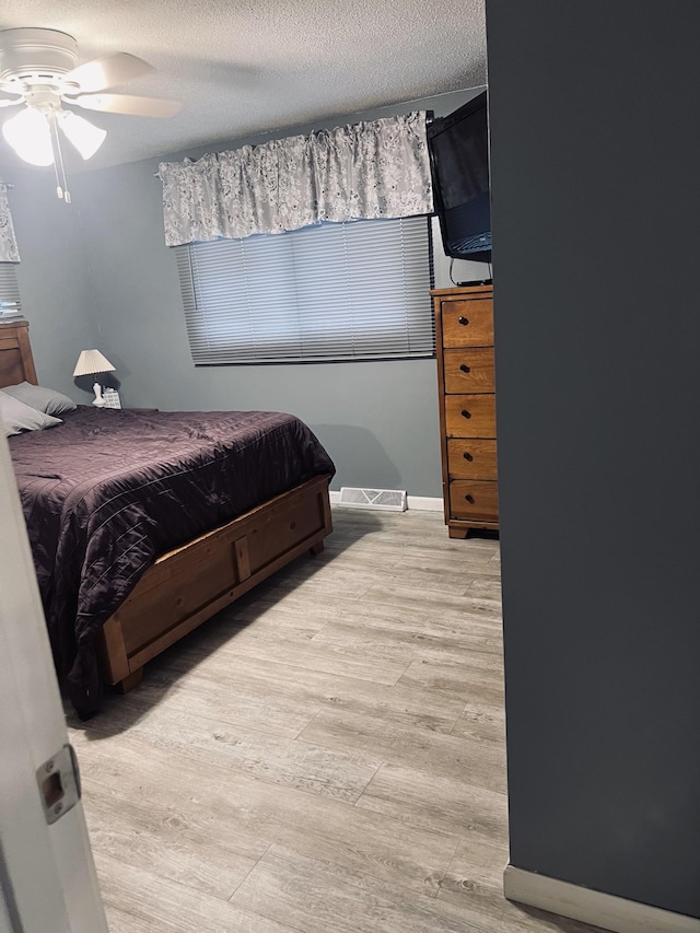 bedroom with visible vents, ceiling fan, a textured ceiling, and light wood finished floors