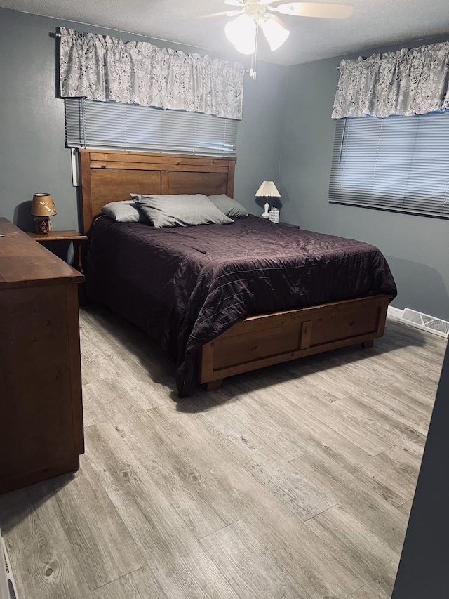 bedroom with visible vents, a ceiling fan, and light wood-style floors