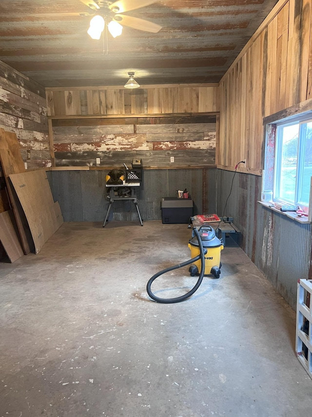 basement with wood walls and a ceiling fan