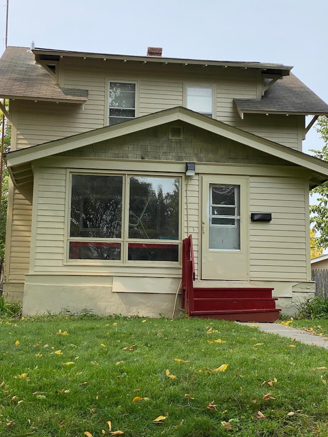 back of house with a yard, a chimney, and entry steps