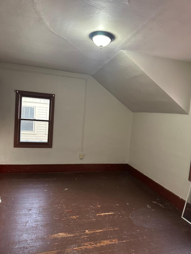 additional living space featuring lofted ceiling, a textured ceiling, and baseboards