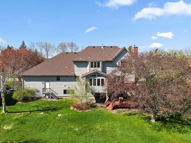 rear view of house featuring a yard, a deck, a chimney, and roof with shingles