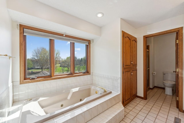 full bath featuring toilet, baseboards, a tub with jets, and tile patterned flooring